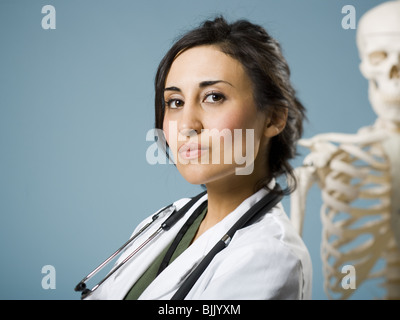 Medico donna sorridente con scheletro in background Foto Stock