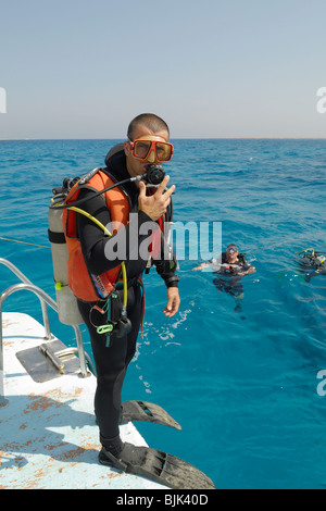 Sommozzatore su una barca prima di fare un grande passo per entrare in acqua Foto Stock