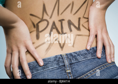 Vista posteriore della donna con le mani sulla parte inferiore della schiena con dolore scritto su di esso Foto Stock