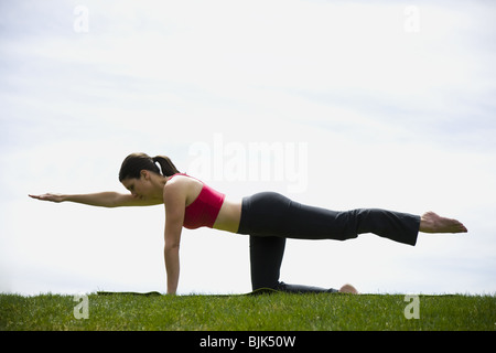 A piena lunghezza profilo di donna stretching sull'erba all'esterno Foto Stock