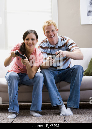 L uomo e la donna seduta su un divano per giocare con i videogiochi di ridere Foto Stock