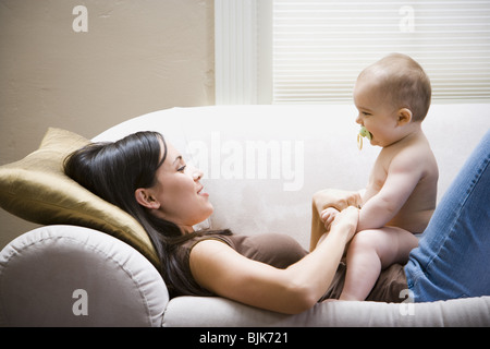 Donna sdraiata sul divano con il bambino Foto Stock