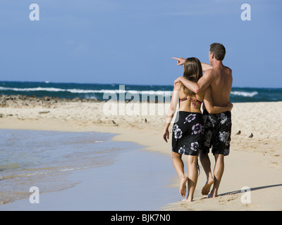 Vista posteriore del giovane camminando sulla spiaggia abbracciando Foto Stock