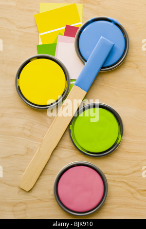 Quattro vernice può coperchi e agitare stick da sopra con scaglie di vernice Foto Stock