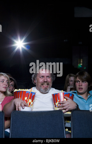 Grande Uomo con secchi di popcorn e drink al cinema teatro tra il giovane Foto Stock