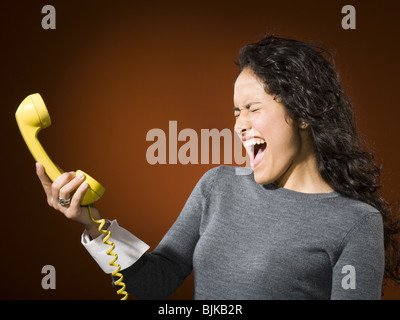 Donna che mantiene telefono retrò e urlare Foto Stock