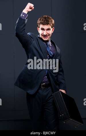 Uomo d affari con valigetta e il braccio fino a sorridere Foto Stock