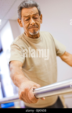 Fisioterapista assistere un uomo anziano con una gamba in piedi Foto Stock