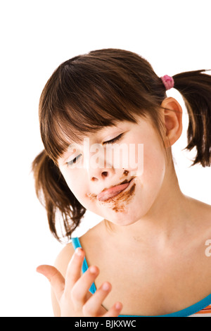 Bambina con pig-tail leccare il cioccolato il suo dito Foto Stock