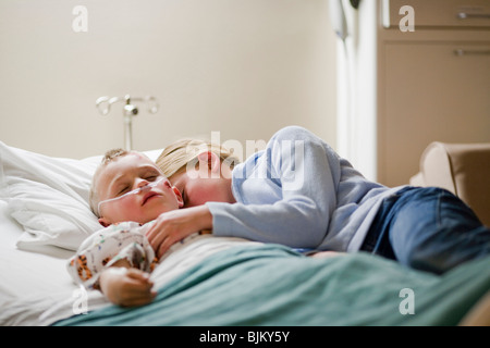 Ragazza che stabilisce con il fratello su letto di ospedale Foto Stock