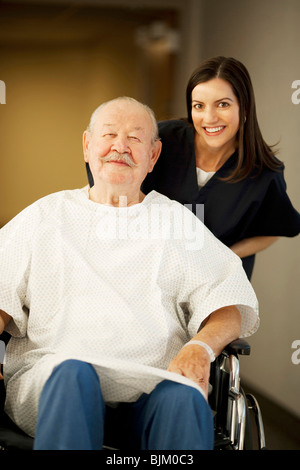 Uomo maturo in abito ospedale con un infermiere sorridente Foto Stock
