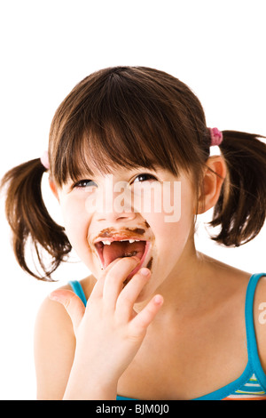 Bambina con pig-tail leccare il cioccolato il suo dito Foto Stock