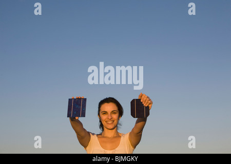 Donna che mantiene due pannelli solari verso il sole Foto Stock