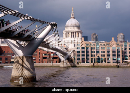 Il London Millenium Bridge con la pietra bianca della Cattedrale di St Paul in background in contrasto contro un grigio scuro sky Foto Stock