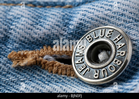 Chiudere l immagine del metallo fascia di cintura fissaggio su una coppia di sbiadito blu jeans denim mostrando i realizzatori nome della marca Foto Stock