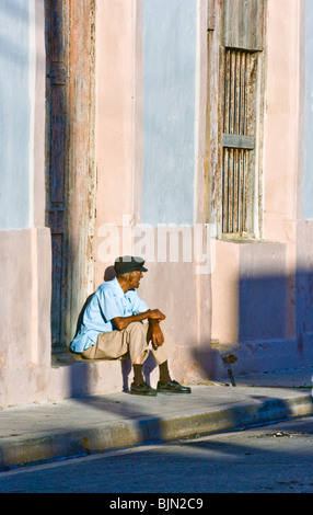 Un cubano uomo anziano a guardare il mondo che passa da in Cardenas e godendo di un sigaro. Foto Stock