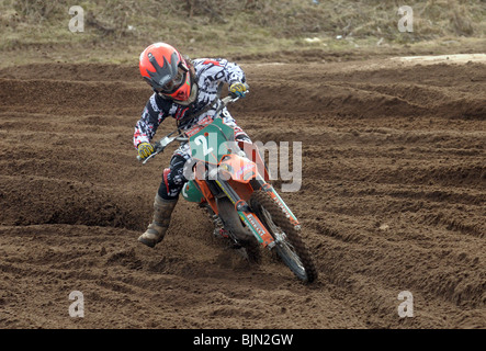 Un ragazzo giovane racer prende una piega sulla sua moto motocross Foto Stock