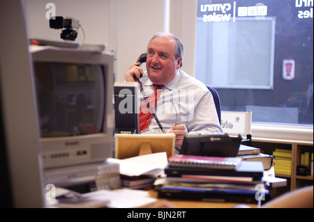 Un giornalista maschio sul telefono lavorano nella radio della BBC del Galles Cymru / Sala stampa ufficio e studio, Aberystwyth Wales UK Foto Stock