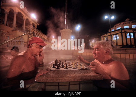 Gli uomini che giocano a scacchi in bagni Szechenyi in una fredda notte invernale a Budapest, Ungheria Foto Stock