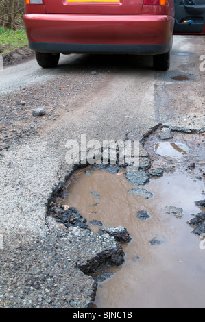 auto e ruota accanto a un vano lasciato in strada a causa del rigido clima invernale Foto Stock