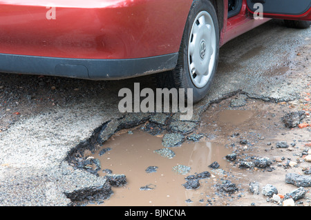 auto e ruota accanto a un vano lasciato in strada a causa del rigido clima invernale Foto Stock