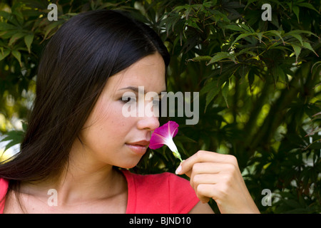 Giovane donna odore di viola fiore nel giardino. Foto Stock