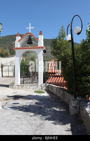Scena tradizionale in un villaggio greco, un arco con una campana e croce. Foto Stock