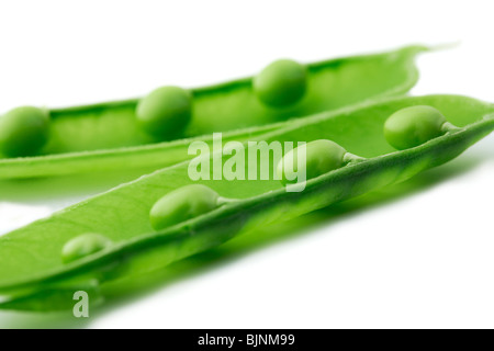 Un close-up di un pea pod split aprire rivelando i piselli su sfondo bianco Foto Stock