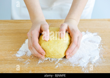 Mani impastare palla di impasto con la farina a fontana sul tagliere Foto Stock