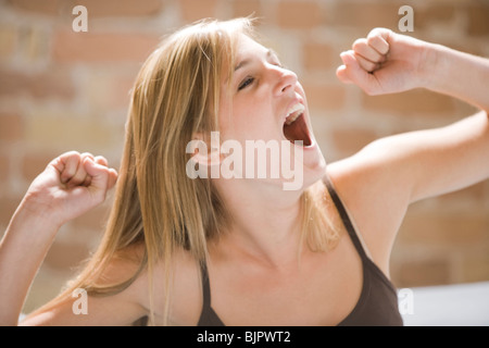 La donna a sbadigliare e stretching nel letto Foto Stock