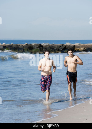 Due uomini in esecuzione sulla spiaggia Foto Stock