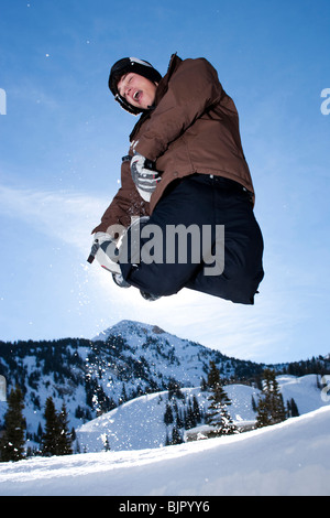 Ragazzo adolescente saltando fuori nella neve Foto Stock