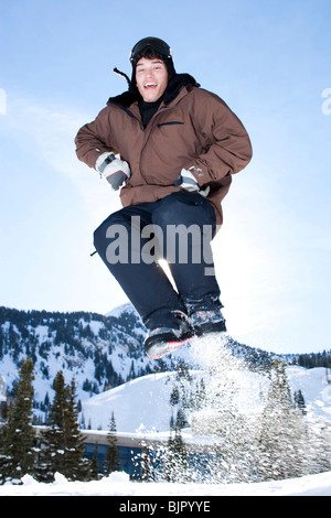 Ragazzo adolescente saltando fuori nella neve Foto Stock