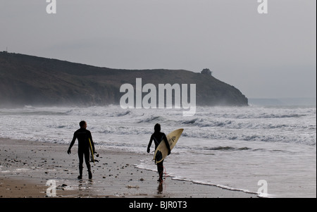 Due surfisti a piedi lungo Praa Sands in Cornovaglia. Foto Stock