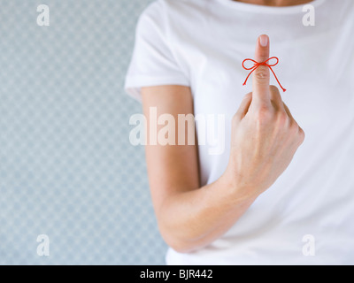 Donna con una stringa di colore rosso legato sul suo dito. Foto Stock