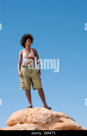 Donna sulla grande roccia gli occhi di schermatura dal sole Foto Stock