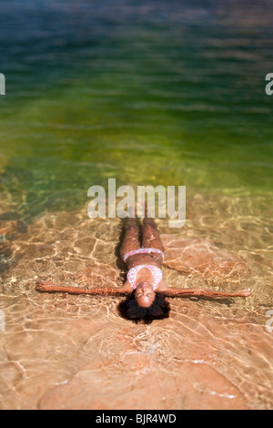 Donna sdraiata in acqua sul retro Foto Stock