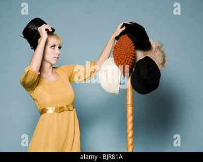 Donna negli anni sessanta costumi cercando su differenti cappelli Foto Stock