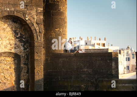 Si tratta di un immagine di un giovane uomo seduto sulle vecchie mura Medina di Essaouira, Marocco. Foto Stock