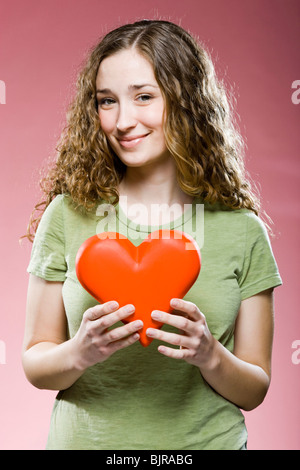 Giovane donna azienda cuore rosso, ritratto Foto Stock