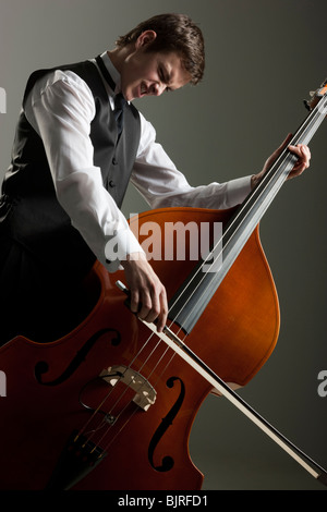 Giovane uomo giocando contrabbasso, studio shot Foto Stock