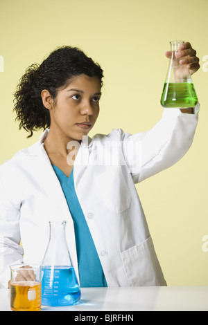 Donna scienziato guardando i prodotti chimici in un laboratorio Foto Stock