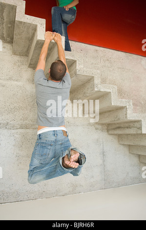 L'uomo appeso sulla scala di cemento Foto Stock