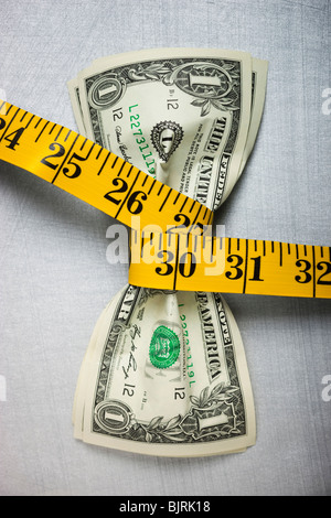 Studio shot di giallo nastro misura la spremitura di due tra le fatture del dollaro Foto Stock