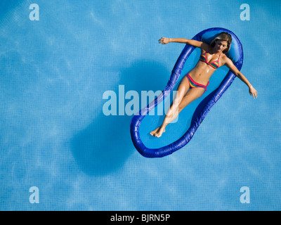 Donna relax sulle sdraio in piscina Foto Stock