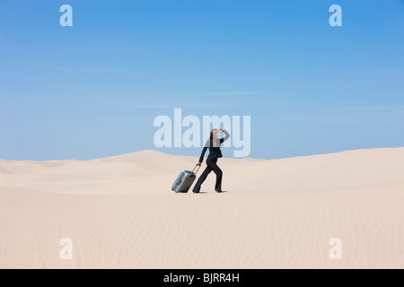 Stati Uniti d'America, Utah, Little Sahara, imprenditrice tirando la valigia nel deserto Foto Stock