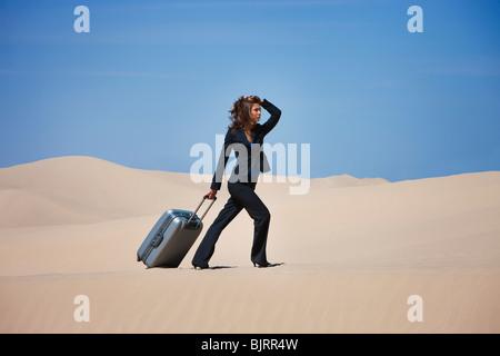 Stati Uniti d'America, Utah, Little Sahara, imprenditrice tirando la valigia nel deserto Foto Stock