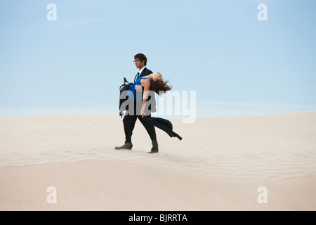 Stati Uniti d'America, Utah, Little Sahara, metà adulto uomo d affari che trasportano giovane donna su deserto Foto Stock