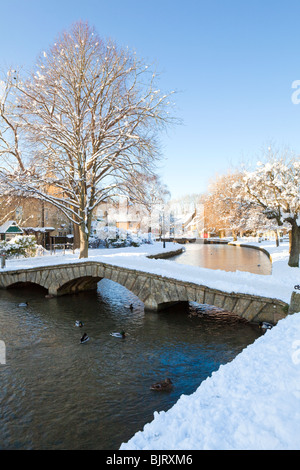 Neve invernale su uno dei ponti sul fiume Windrush nel villaggio di Cotswold di Bourton sull'acqua, Gloucestershire UK Foto Stock