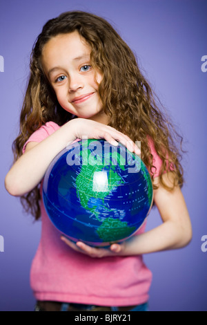 Ragazza giovane appoggiato su di un globo terrestre Foto Stock